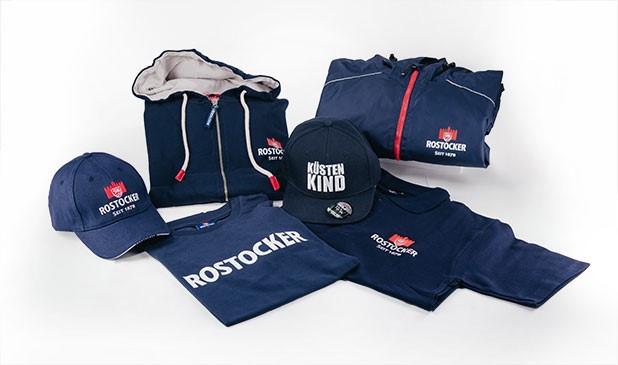 Verschiedene Bekleidungsstücke und Accessoires in Blau sind auf weißem Hintergrund angeordnet.