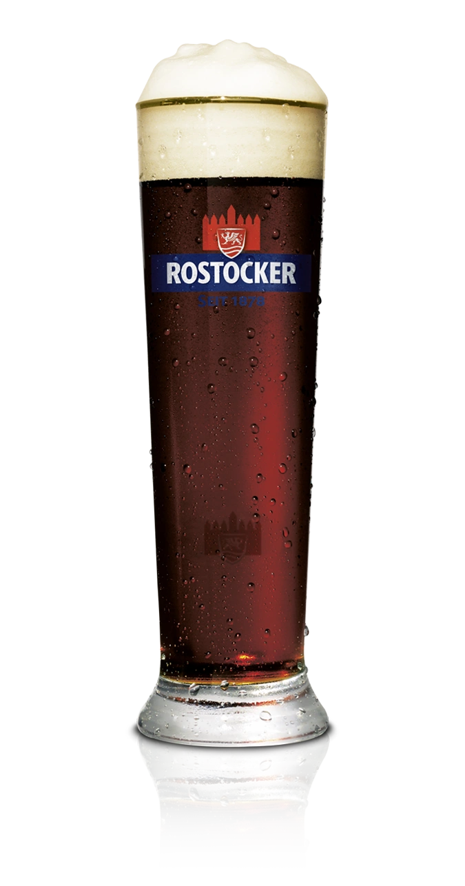 Ein dunkles Bier mit cremefarbenem Schaum steht in einem Glas.