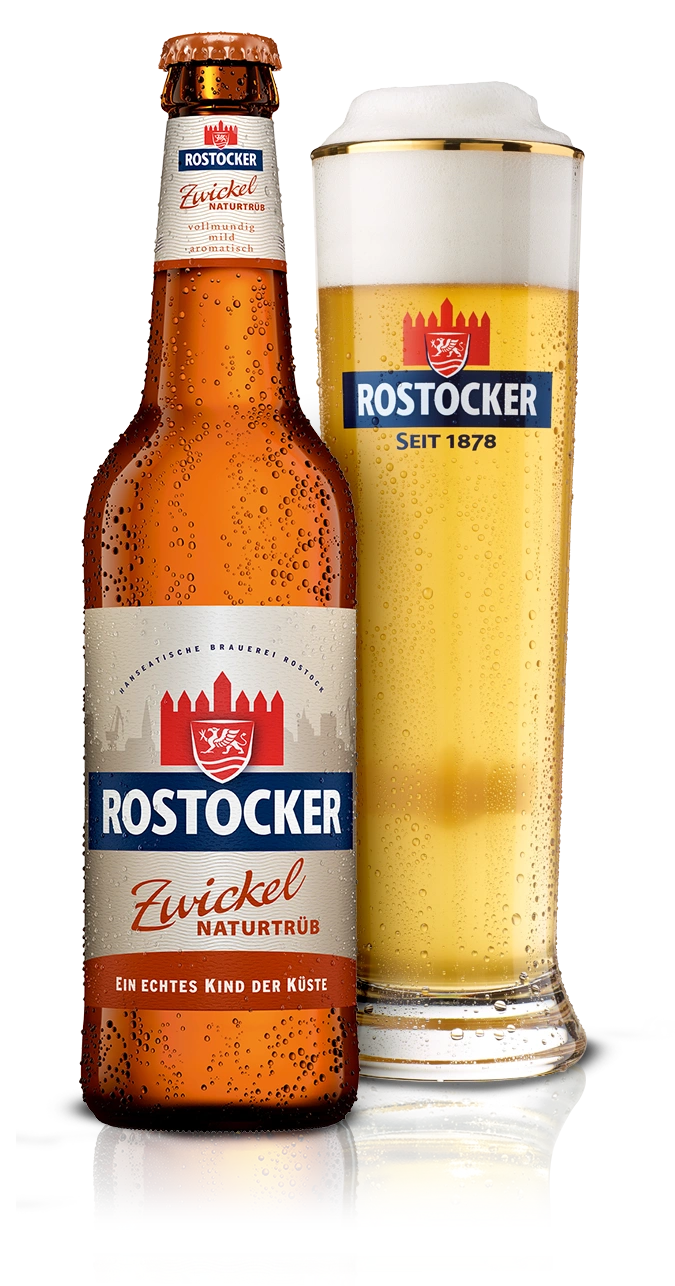 Eine Flasche und ein Glas mit einem schaumigen Getränk stehen nebeneinander. Das Glas ist zur Hälfte gefüllt.